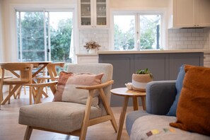 A modern kitchen with a dining area, featuring wooden furniture and a view of greenery outside. - Old Majors Family 4-Bed Retreat Southern Highlands (Braemar)