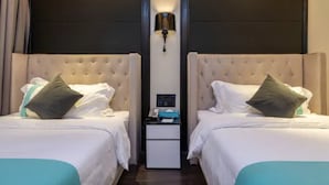 Une chambre d’hôtel avec deux lits, une table de chevet et un luminaire fixé au mur.
