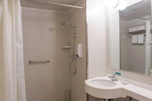 Un bagno con doccia, lavandino e specchio.