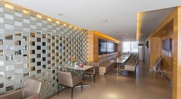 A modern dining area with a high table and chairs, a partition wall, and a long counter with seating.