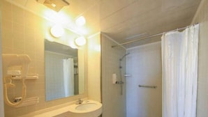 Ein Badezimmer mit Waschbecken, Spiegel und Duschbereich.