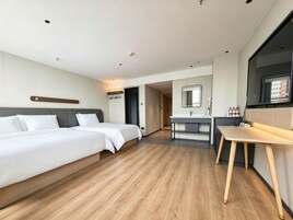 A hotel room with two beds, a bathroom, and a small table.