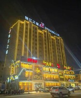 A multi-story hotel with illuminated signage, a prominent entrance, and a parking area in front.