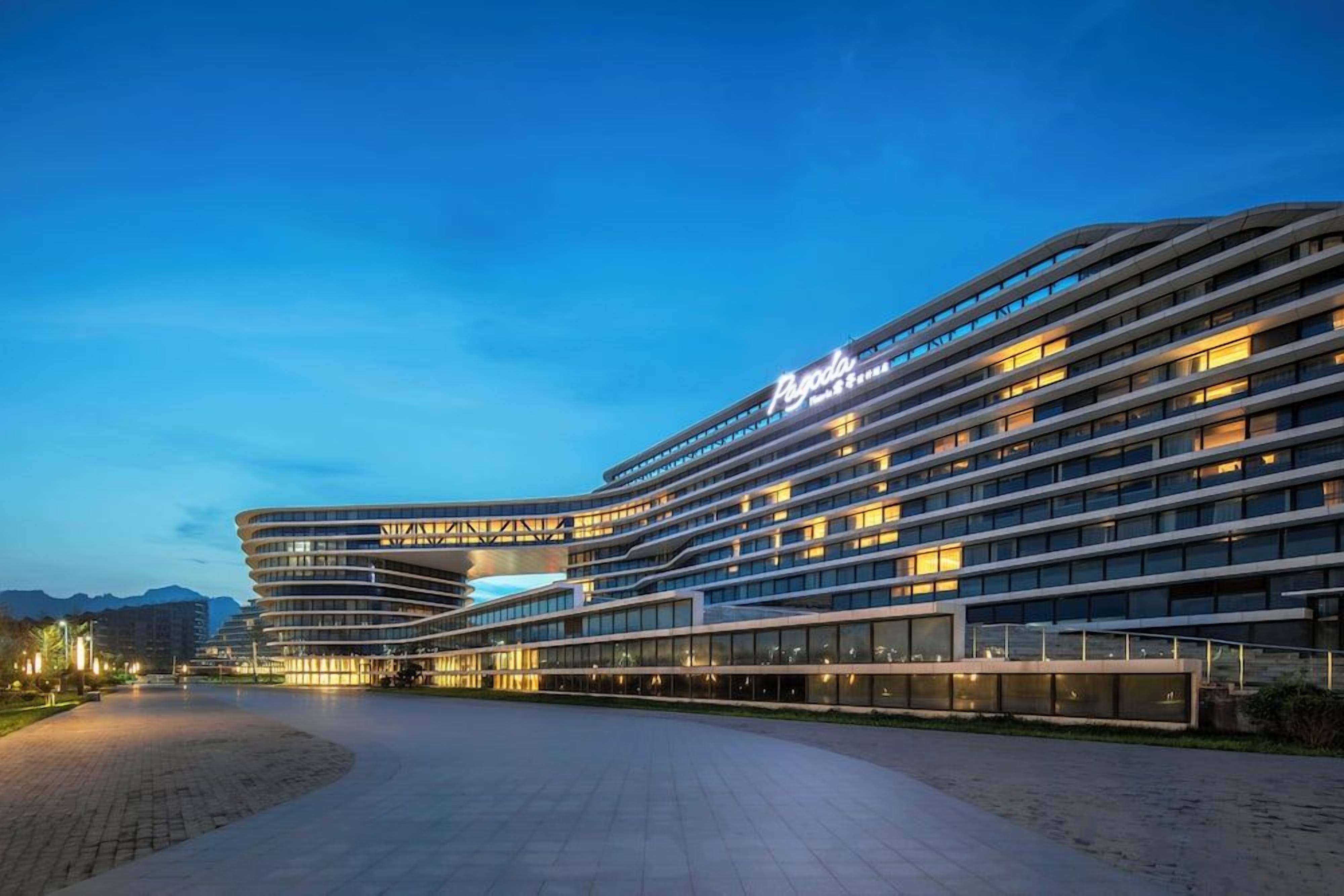 A modern hotel with a curved facade, multiple floors, and a well-lit entrance area.