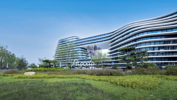 Et moderne hotel med en buet facade, flere etager og en velplejet have.