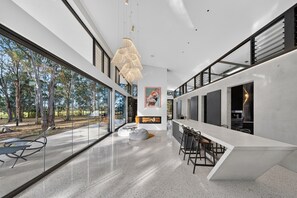 A modern kitchen with a large island, bar stools, and a view of the outdoors.