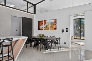 A modern kitchen with a dining area, featuring a large island, black chairs, and a dining table.