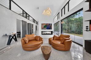 A modern living room with two leather sofas, a coffee table, and a large abstract painting on the wall.