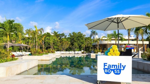 A poolside area with lounge chairs, a water feature, and a cart labeled 'Family Boss' with towels. - Family Selection At Grand Palladium Kantenah Resort & Spa (Kantenah)