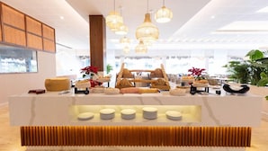 A modern reception area with a central counter displaying food items, surrounded by hanging pendant lights. - Family Selection At Grand Palladium Kantenah Resort & Spa (Kantenah)