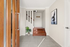 Ein Flur mit einer Holztreppe, einem Blumentopf und einem gerahmten Bild an der Wand.