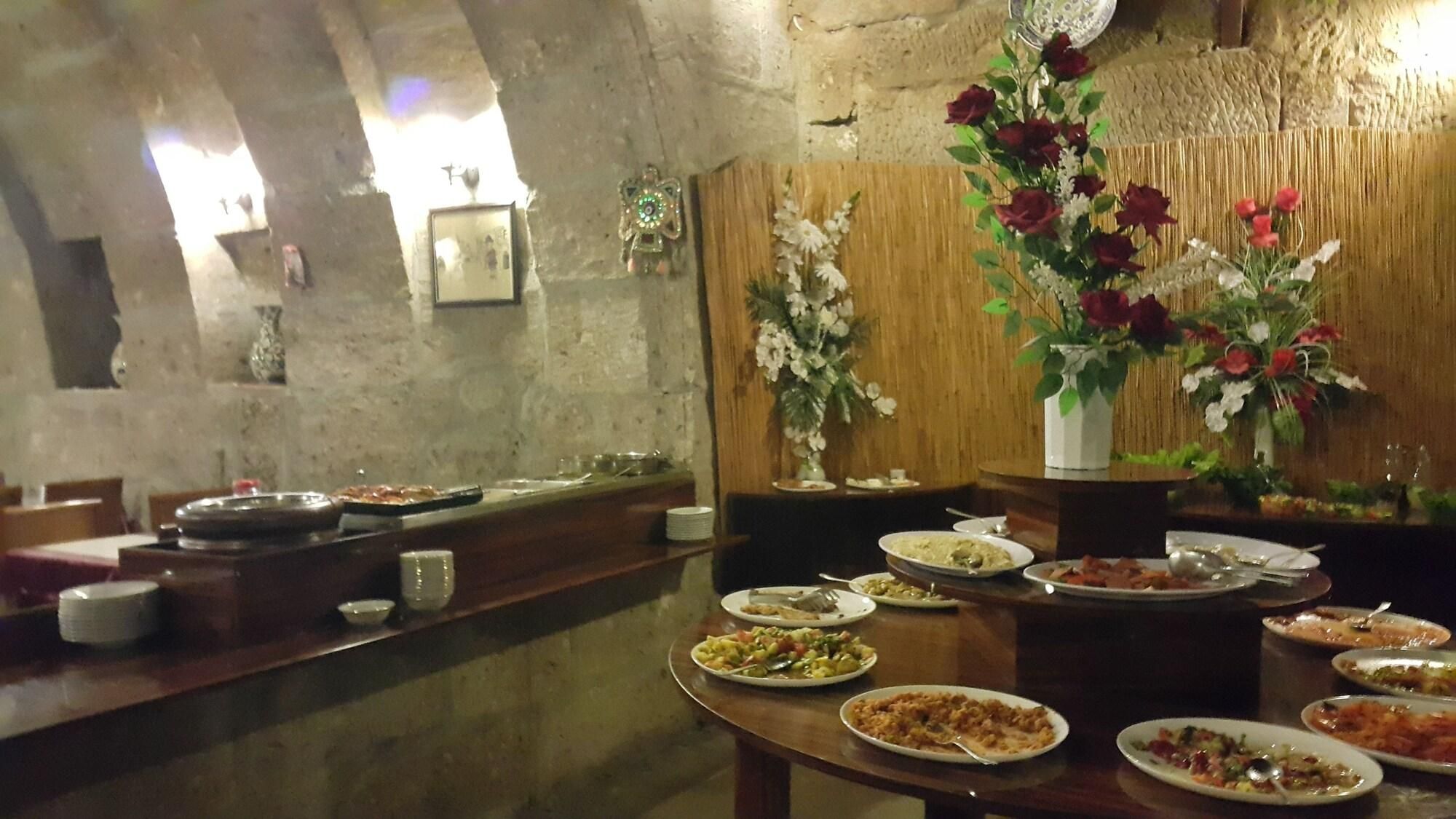 A dining area with multiple tables set for meals, a wooden wall with decorative elements, and a stone wall in the background.