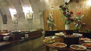 Un comedor con varias mesas dispuestas para comer, una pared de madera con detalles decorativos y una pared de piedra al fondo.