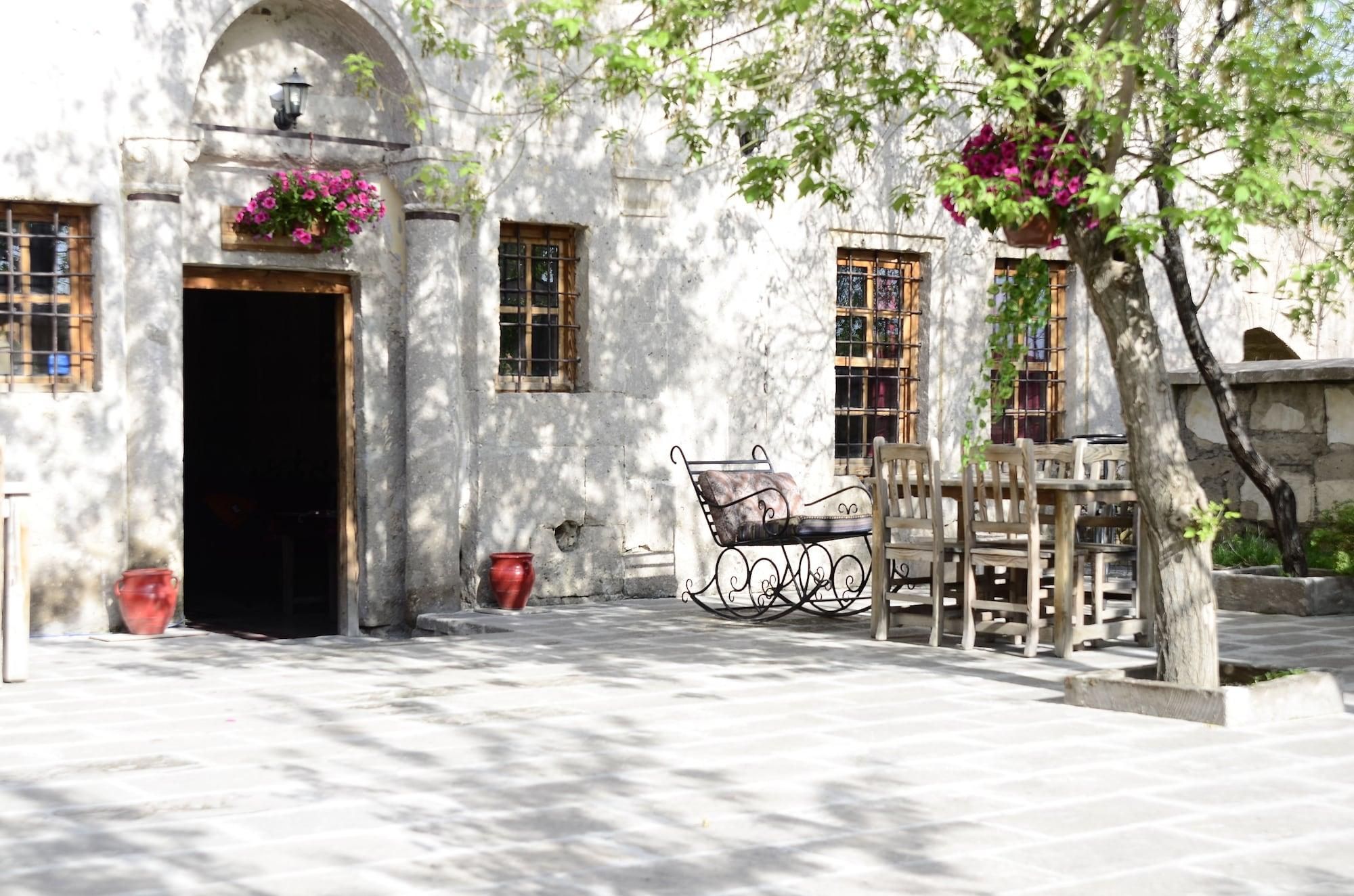 A courtyard with a bench, a door, and a window with a flower basket.