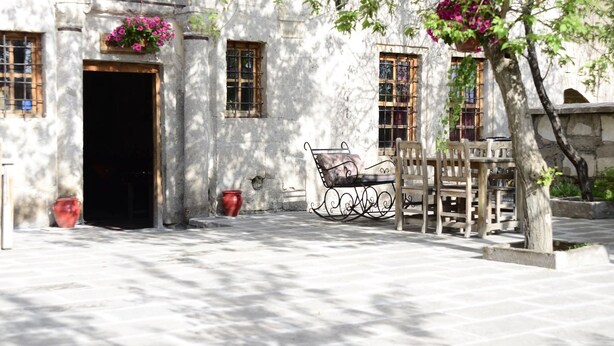 Un patio con un banco, una puerta y una ventana con un cesto de flores.
