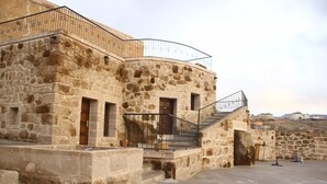 Un edificio de piedra con un balcón curvo y una escalera que lleva a un nivel superior.