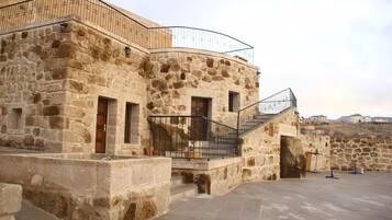 A stone building with a curved balcony and a staircase leading to an upper level.