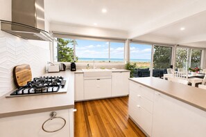 Eine moderne Küche mit Gasherd, weißen Schränken und Blick auf den Strand.