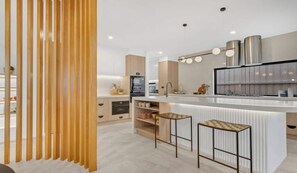 A modern kitchen with a central island, bar stools, and a wooden partition. - Spacious 4-Bed Family House Near Gateway Plaza (Leopold)