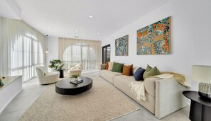 A modern living room with a sofa, coffee table, and artwork on the wall. - Spacious 4-Bed Family House Near Gateway Plaza (Leopold)