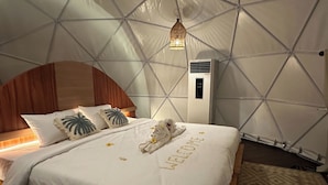 Una habitación con cama, cabecera de madera, aire acondicionado de pared y techo con estampado geométrico.
