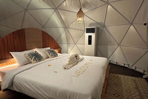 Une chambre avec un lit, une tête de lit en bois, un climatiseur fixé au mur et un plafond orné de motifs géométriques.