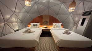 Un espacio acogedor con forma de tienda que incluye dos camas, una mesa central y almohadones decorativos.