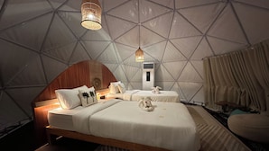 Una habitación tipo tienda con cama, almohadas, una lámpara colgante y un calentador.