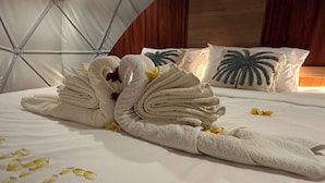 Una cama con una decoración de toallas en forma de cisne y una almohada con forma de hoja de palma.