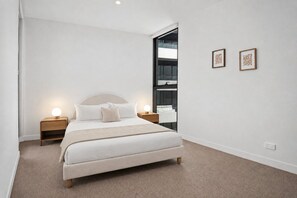Une chambre à coucher moderne avec un lit, des lampes de chevet et deux œuvres d’art encadrées accrochées au mur.
