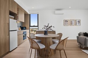 Eine moderne Küche mit Essbereich, ausgestattet mit einem runden Tisch und Stühlen, Blick auf die Stadt und einem großen Fenster.