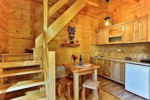 A wooden interior with a kitchen area, wooden staircase, and a dining table with chairs. - Garni Eco Hotel Elite Kolasin (Kolašin)