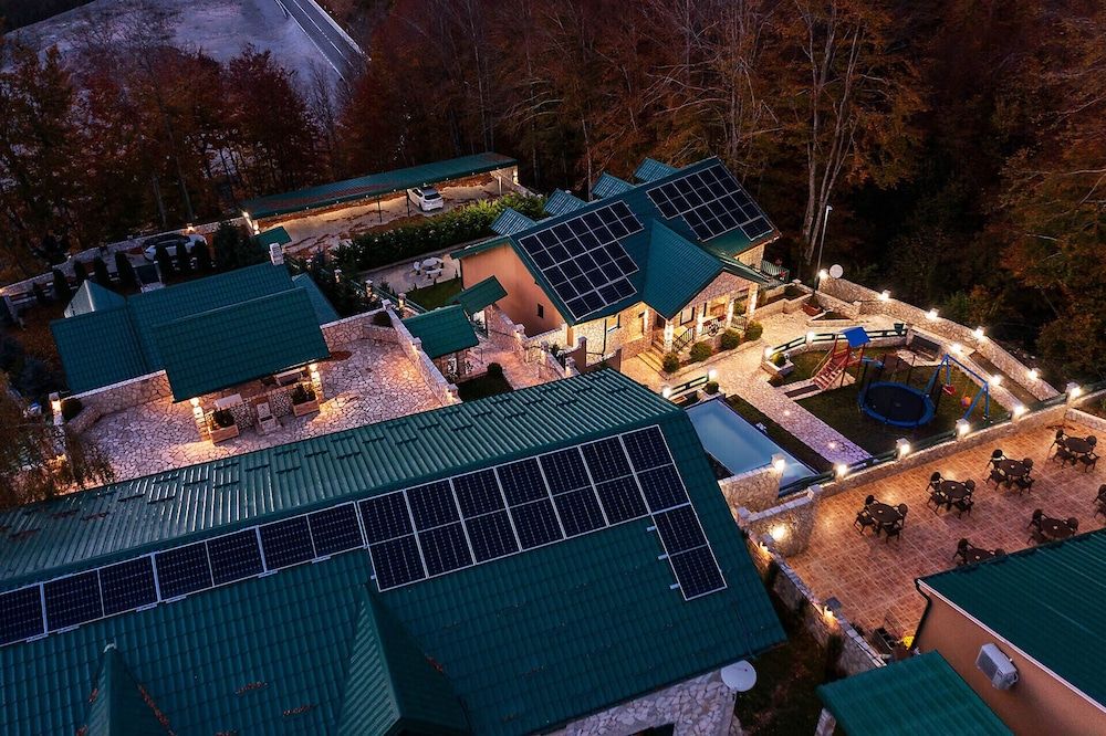 A resort with multiple buildings, solar panels on roofs, outdoor seating, and a swimming pool.