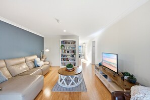 Een moderne woonkamer met een leren bank, een houten salontafel, een boekenkast en een flatscreen televisie.