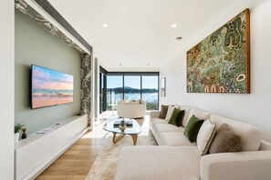 Ein modernes Wohnzimmer mit einem großen Flachbildfernseher, einem Sofa, einem Couchtisch und einem Gemälde an der Wand.
