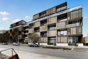 Um edifício residencial com vários andares, varandas, grandes janelas e design arquitetônico moderno.
