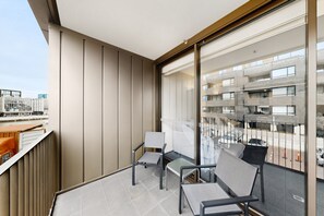 Un balcó amb vista a un edifici modern, dues cadires i una taula petita.