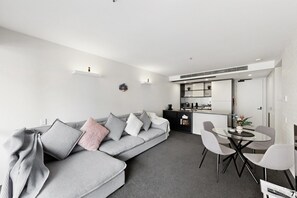A modern living room with a grey sofa, a dining table with chairs, and a kitchen area in the background. - Executive 2-Bed Apartment Near Kingston Hub (Kingston)