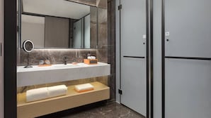 Un baño moderno con tocador de mármol, un espejo grande, toallero y vestidor.