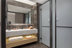Et stilfuldt badeværelse med en marmorvask, et stort spejl, en håndklædetørrer og et walk-in closet.