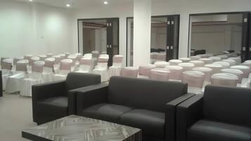A conference room with rows of chairs, a coffee table, and a large mirror.