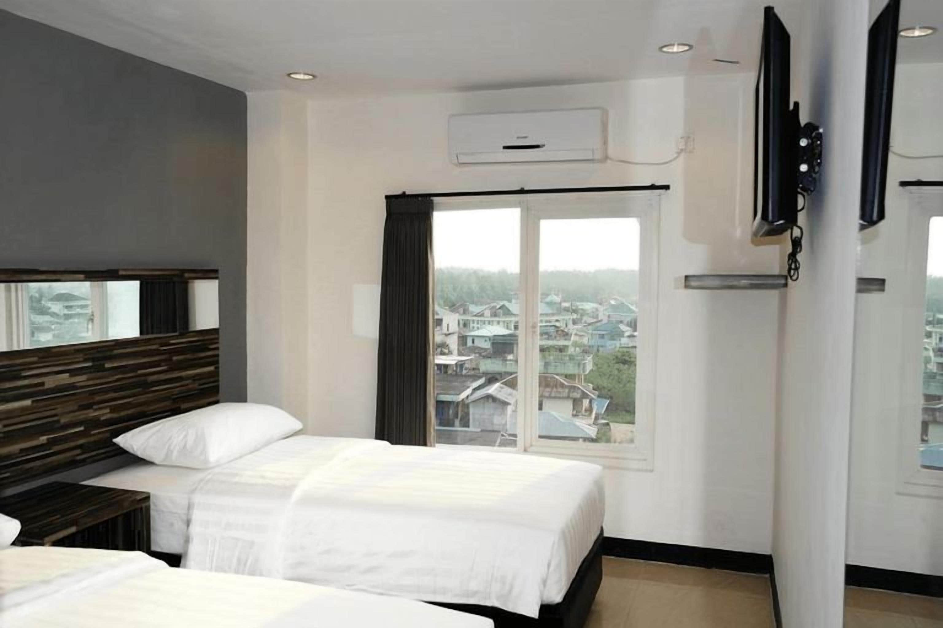 A hotel room with two beds, a large window with a view, and a mounted TV.