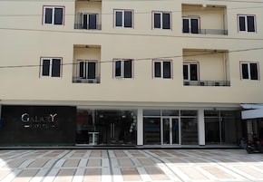 A hotel with a modern facade, multiple balconies, and a storefront with a sign.