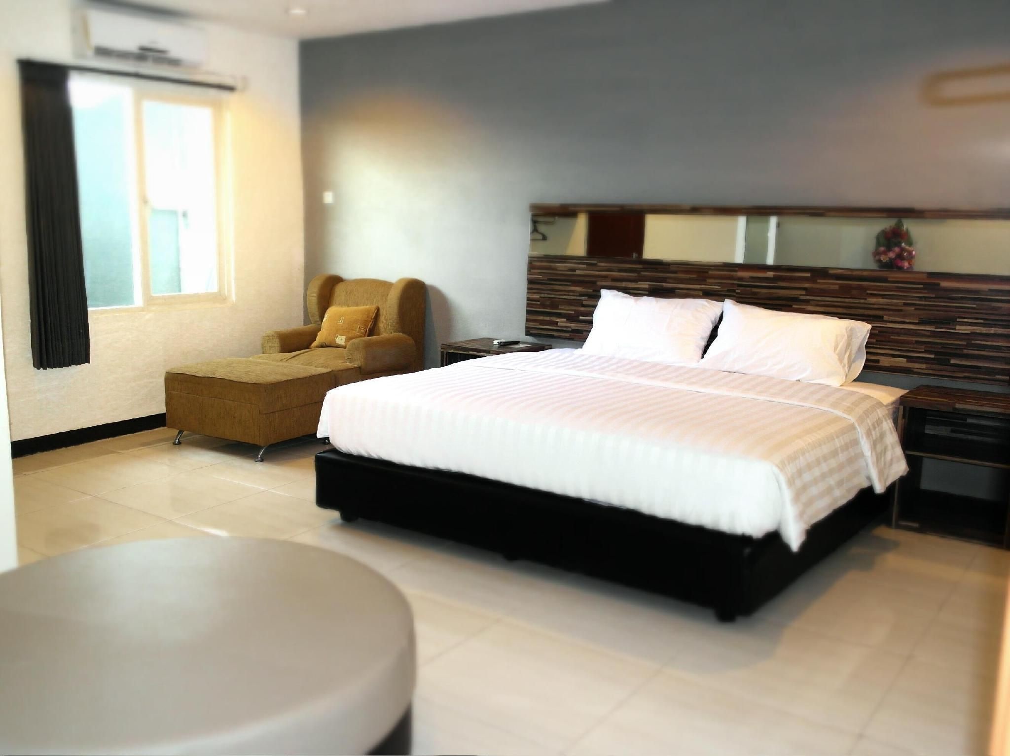 A modern hotel room with a large bed, a sofa, a small table, and a mirror on the wall.