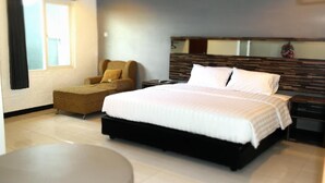 A modern hotel room with a large bed, a sofa, a small table, and a mirror on the wall. - Galaxy Hotel (Tarakan)