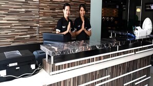 A reception desk with a modern design, a counter, and a wall with a wood-like pattern. - Galaxy Hotel (Tarakan)