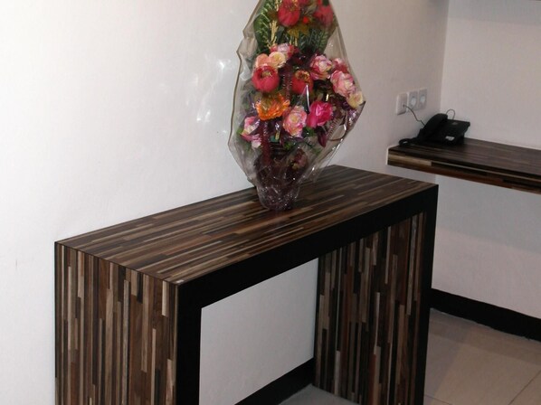 A reception desk with a vase of flowers on a wooden stand. - Galaxy Hotel (Tarakan)