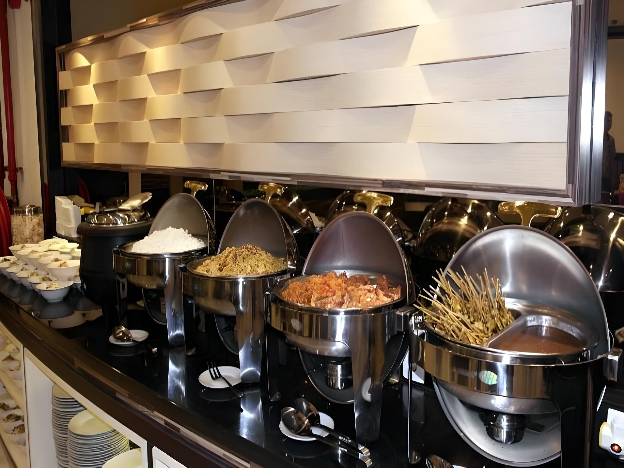 A buffet with various food items in metal containers, including rice, fried chicken, and vegetables.