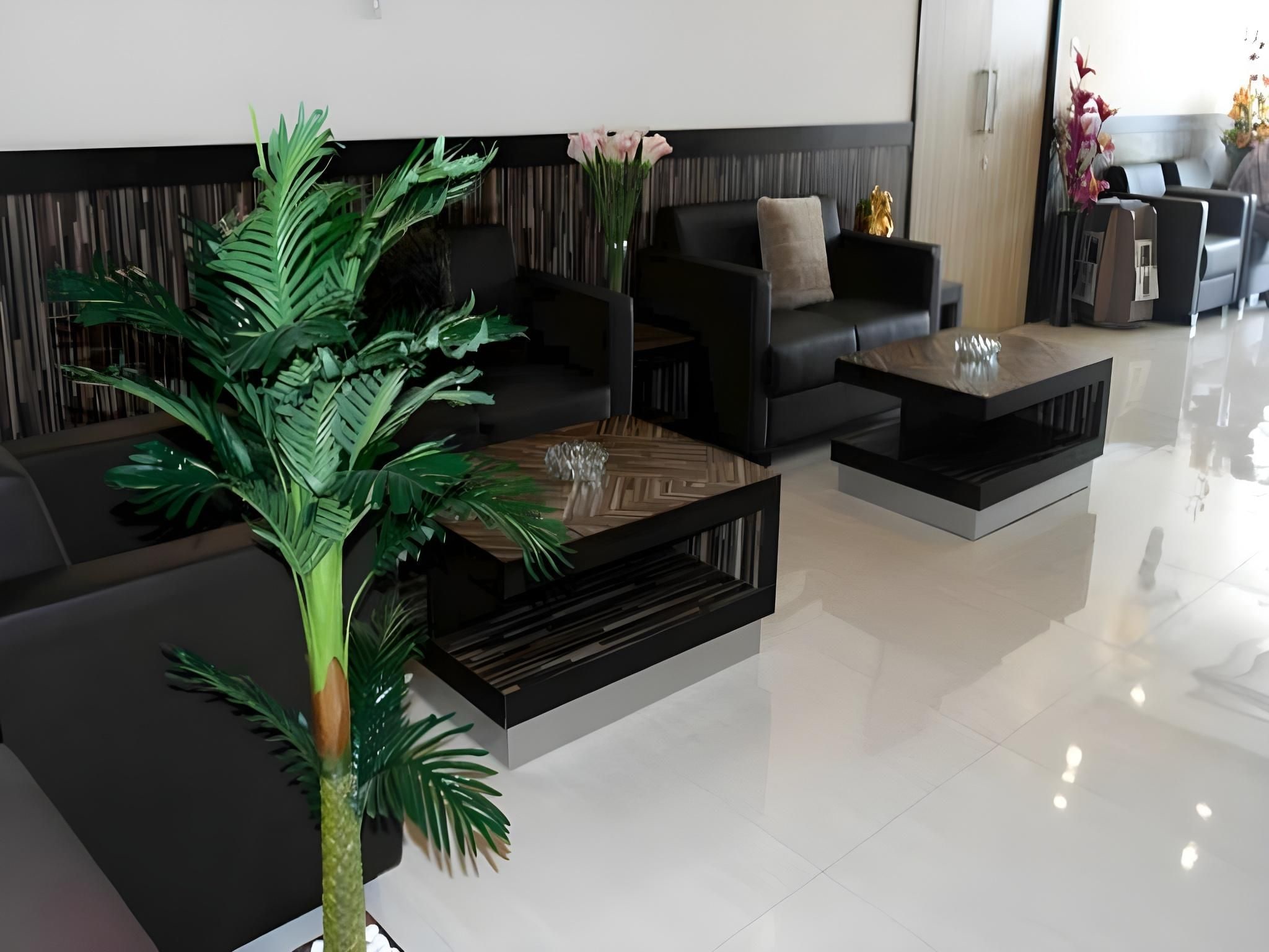A modern living room with a sofa, coffee table, and a large artificial plant.