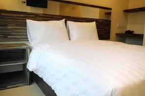 A neatly made bed with white bedding in a hotel room. - Galaxy Hotel (Tarakan)